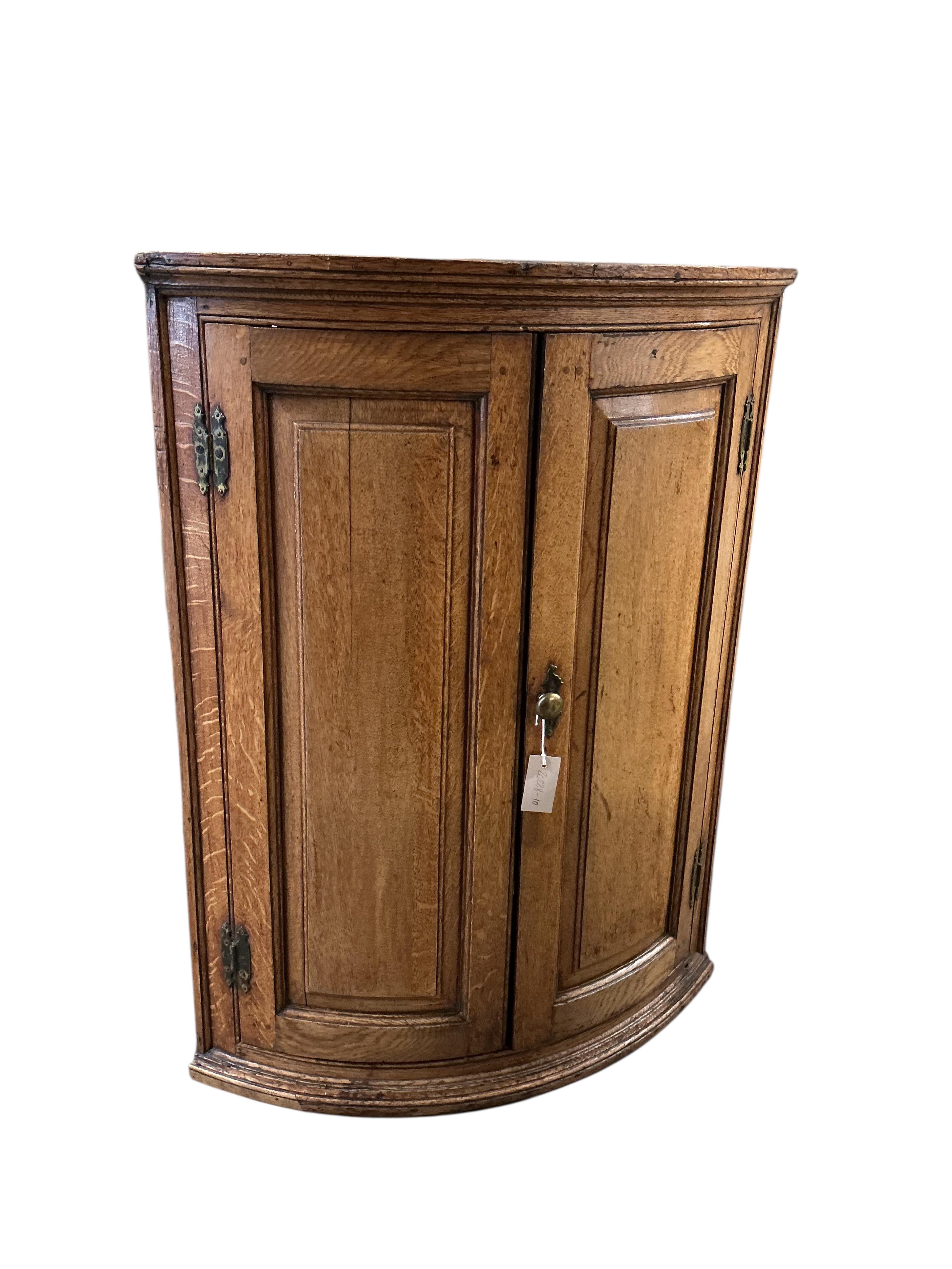 An early 19th century oak bowfront hanging corner cupboard, width 72cm, depth 49cm, height 97cm.